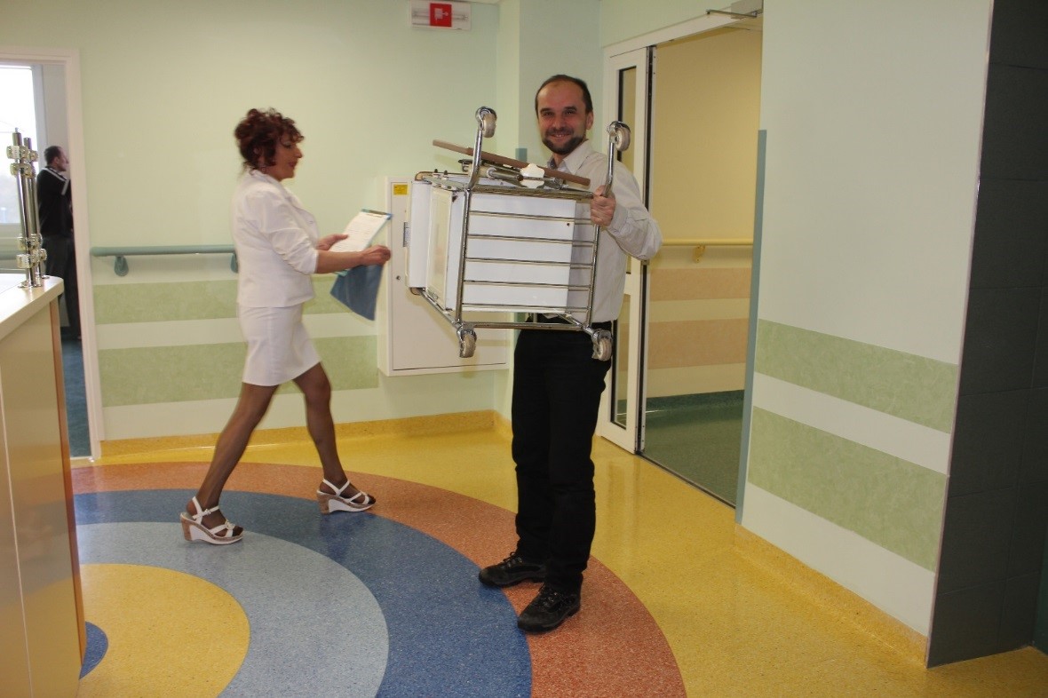 Uśmiechnięty mężczyzna niosący w rękach w&oacute;zek ze sprzętem